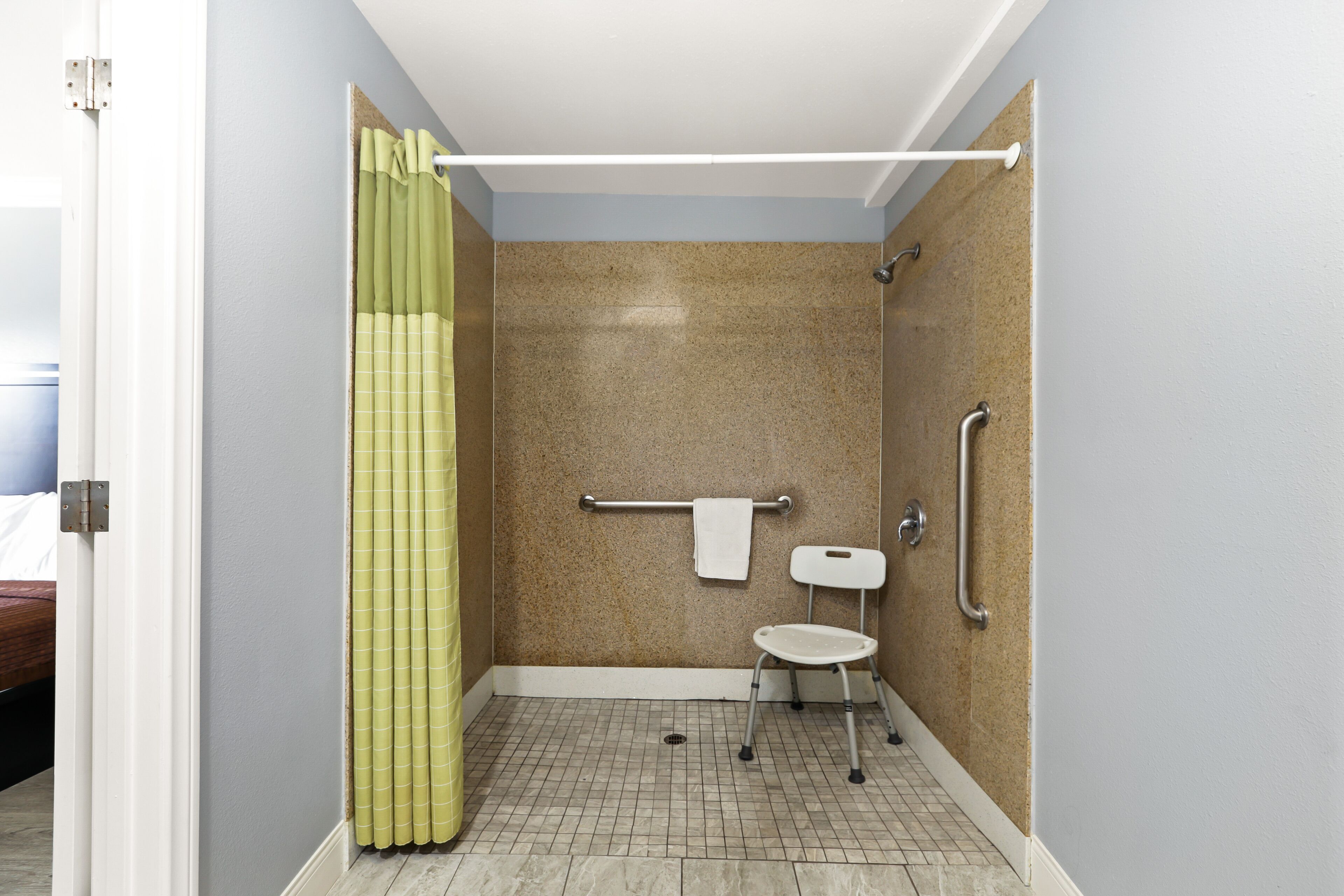 A modern bathroom with a shower, grab bars, and a wheelchair-accessible bench.