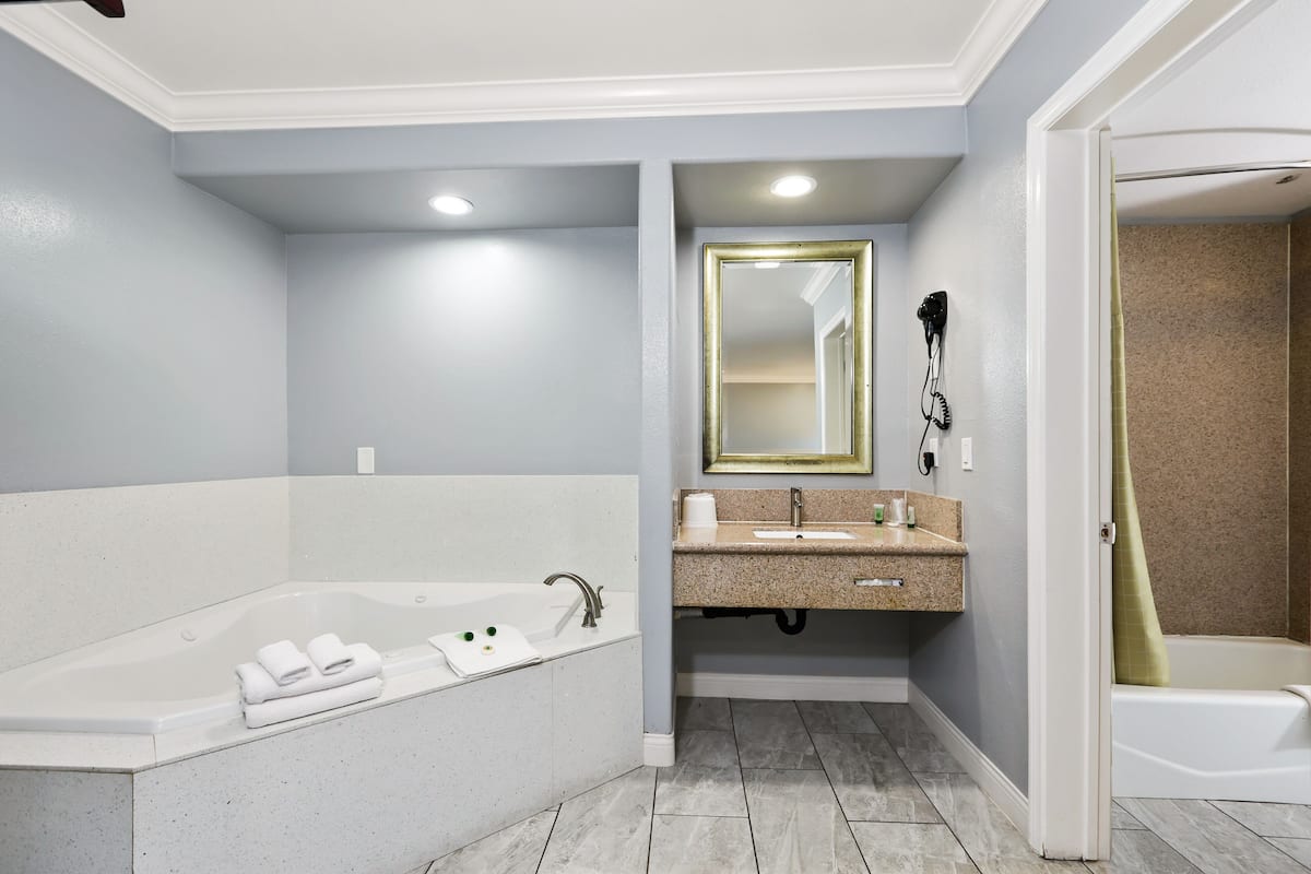 A modern bathroom with a freestanding bathtub, a vanity with a mirror, and a shower area.
