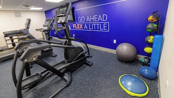 Un gimnasio con cintas de correr, pelotas de ejercicio y una pared con mensajes motivacionales.