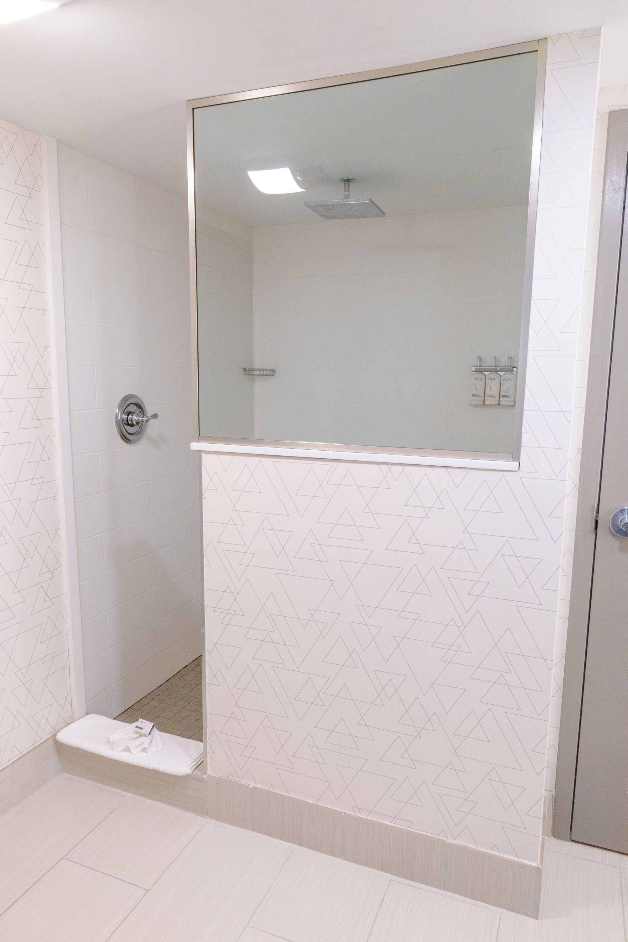 A bathroom with a shower, a mirror, and a towel rack.