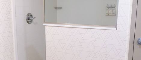 A bathroom with a shower, a mirror, and a towel rack.