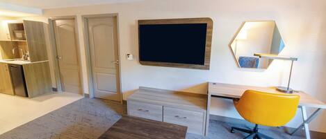 Una habitación moderna con escritorio, silla y televisión de pantalla plana montada en la pared.