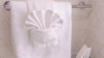 A bathroom with a white towel hanging on a towel rack, a tissue box, and a geometric-patterned wall.