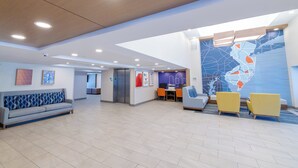 A spacious lobby with a modern design, featuring a seating area with sofas and chairs, a reception desk, and a large wall map.