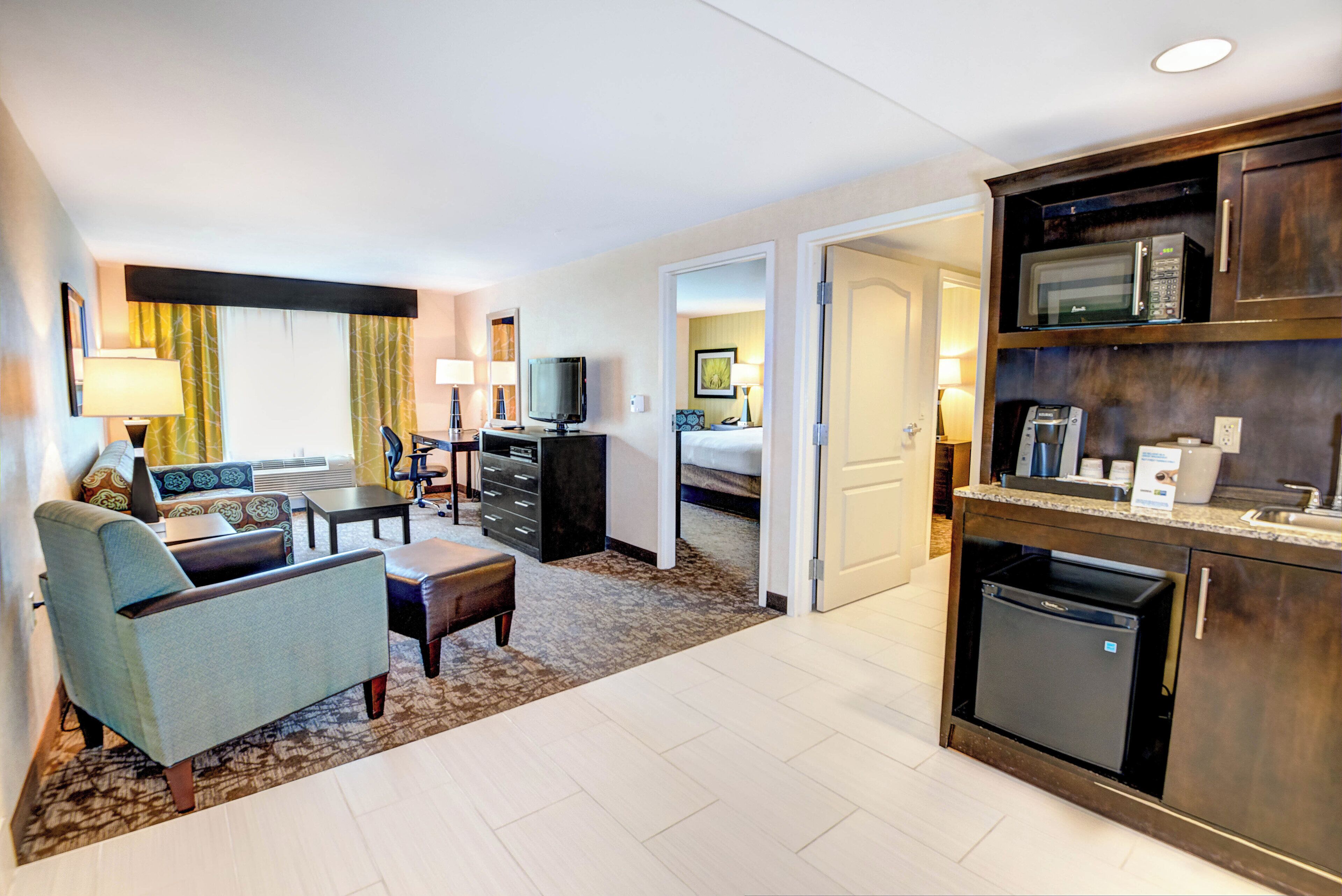 Habitación de hotel con sala de estar, kitchenette y un dormitorio separado.