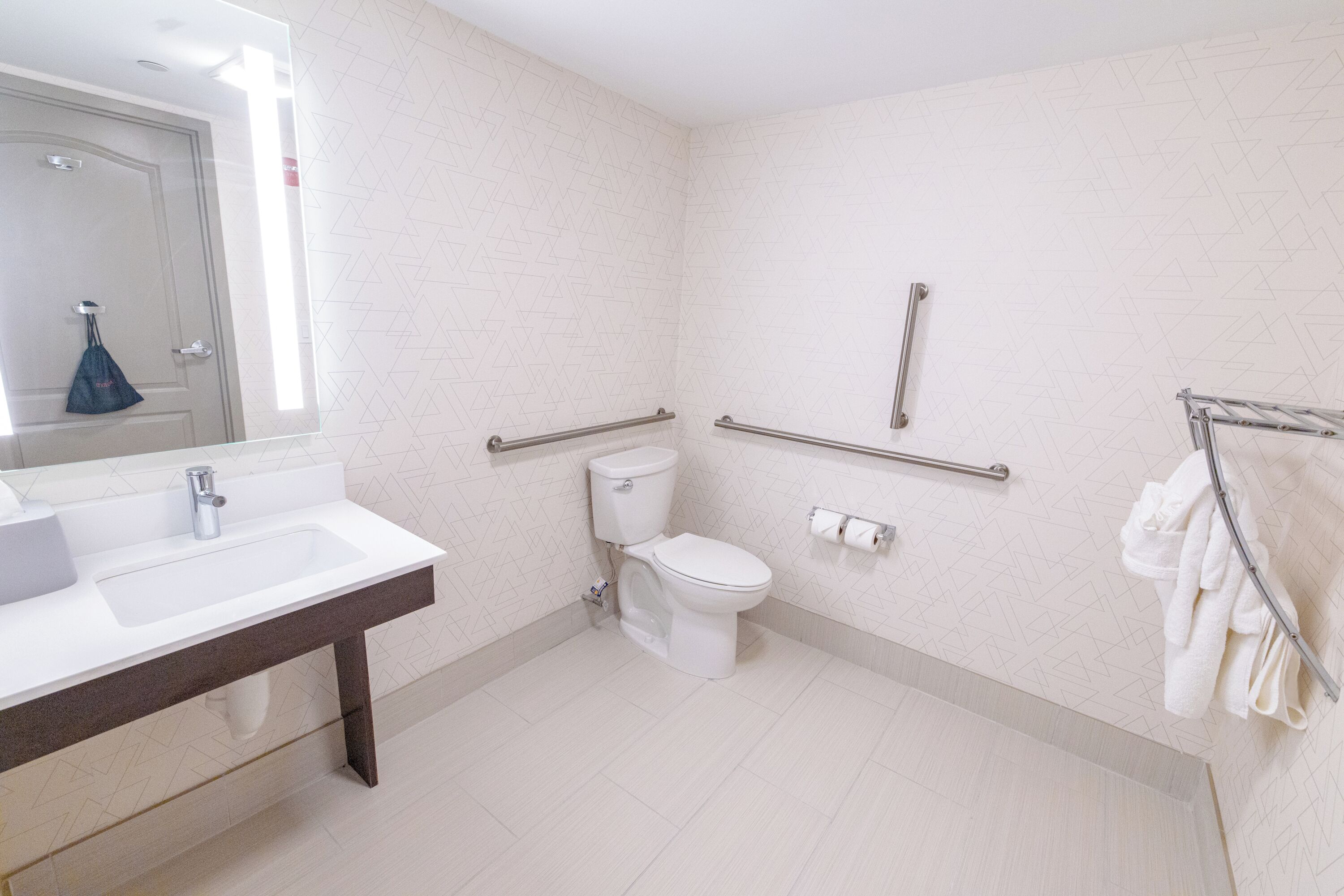 A bathroom with a white sink, toilet, and handrails.