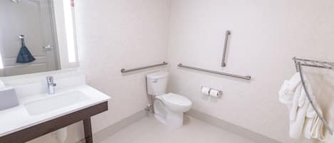Un baño con lavamanos, inodoro y barras de apoyo.