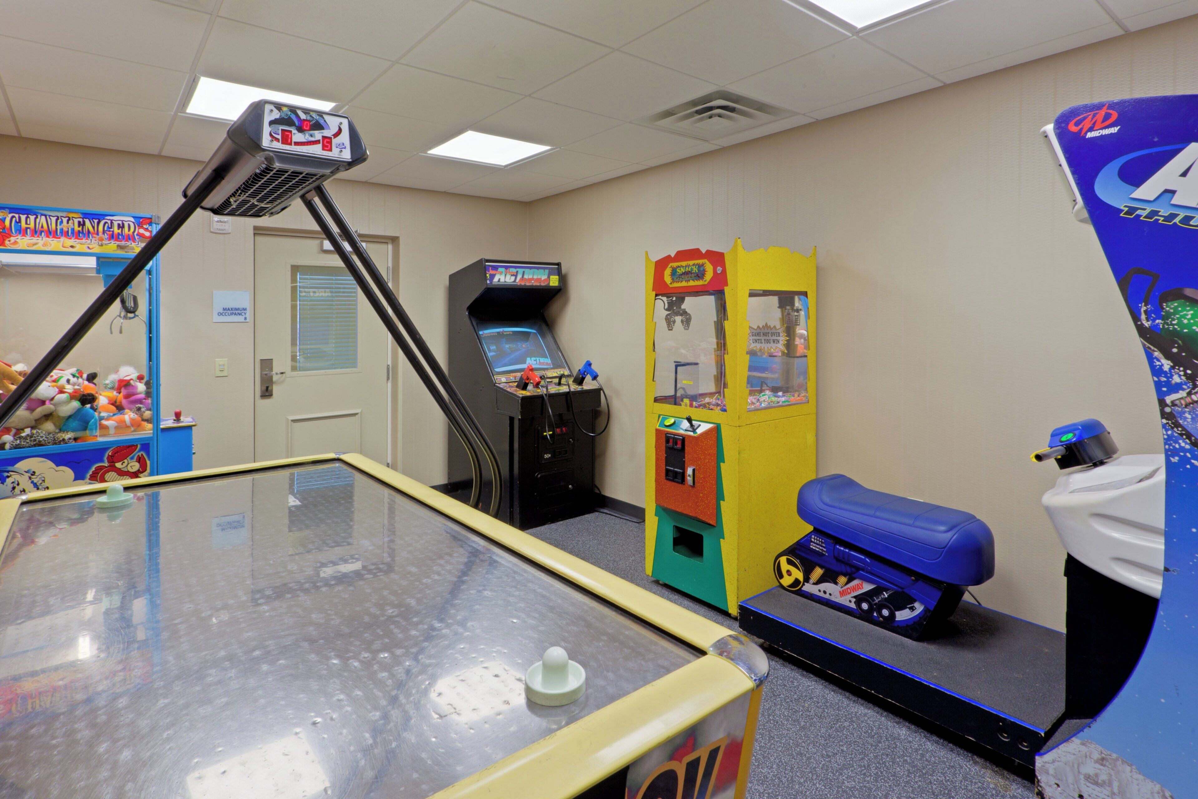A room with a pool table, arcade games, and a vending machine.