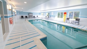 An indoor swimming pool with clear lane markings, lounge chairs, and safety equipment.