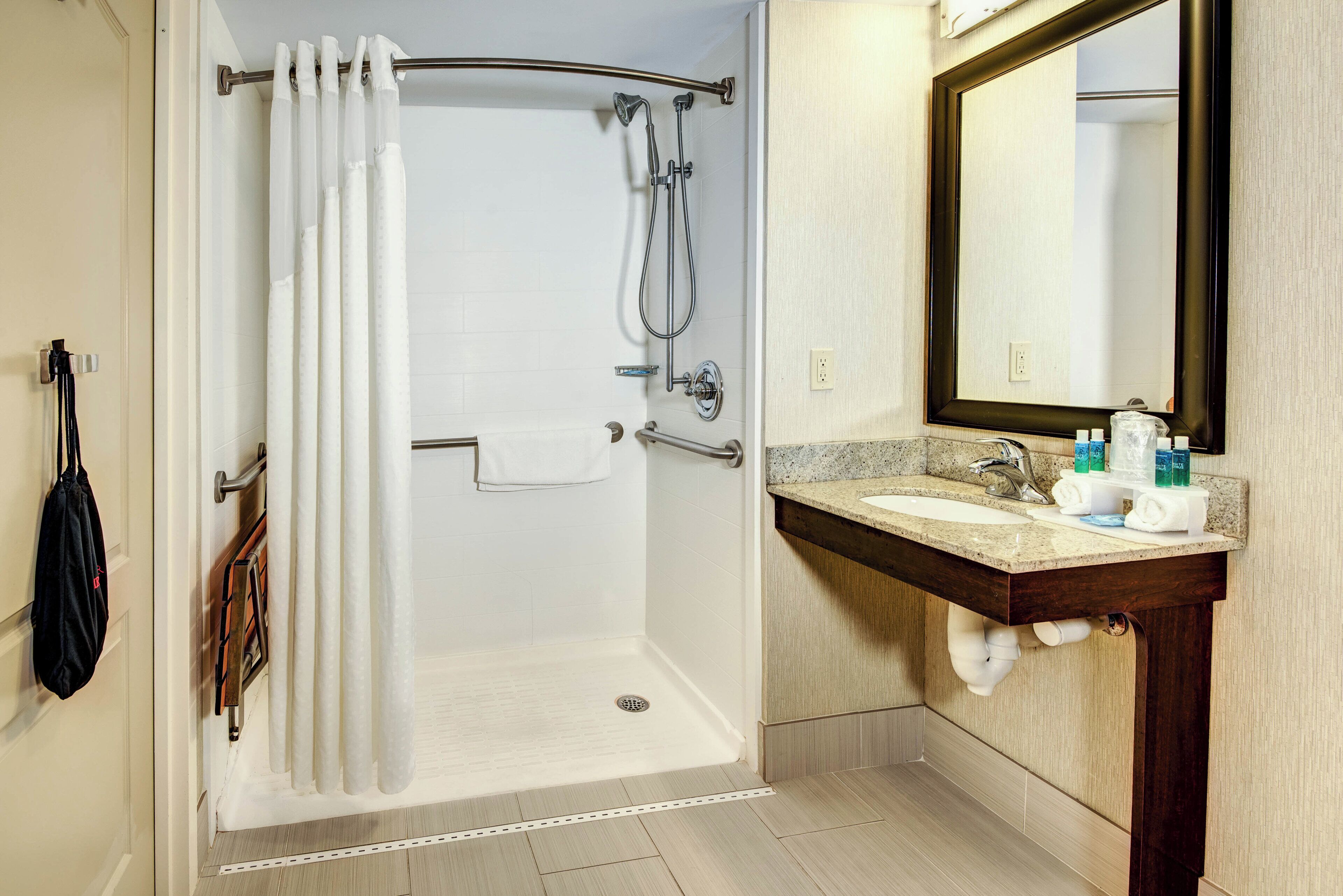 Un baño con ducha, lavamanos y espejo.