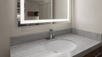 Un baño con encimera de granito, un lavabo blanco, un grifo moderno y un espejo con luz.