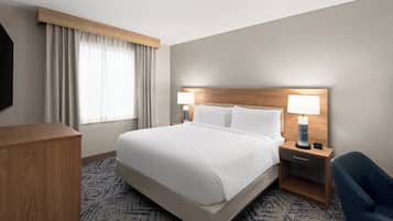 Ein Hotelzimmer mit einem großen Bett, zwei Nachttischen inklusive Lampen, einem Holz-Kopfteil, einem Schreibtisch und einem Stuhl.