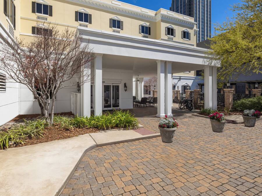 A hotel with a covered patio, outdoor seating, and potted plants.