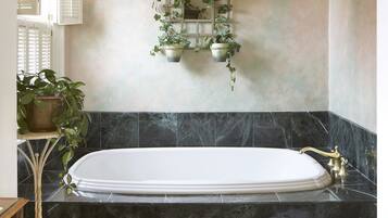 A bathroom with a freestanding bathtub, a wall-mounted plant shelf, and a metal towel rack.