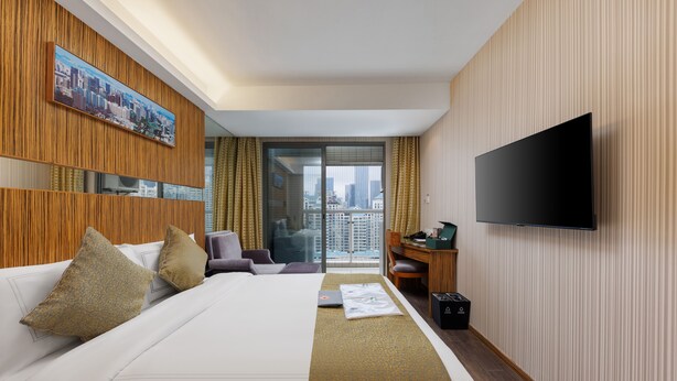 Een hotelkamer met een groot bed, een bureau, een televisie en uitzicht op de stad.
