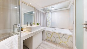 Een moderne badkamer met een douchecabine van glas, een wastafel met twee wastafels, een grote spiegel en een betegelde achterwand met een patroon.