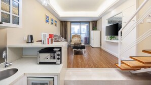 Een moderne keuken met een magnetron, spoelbak en een eethoek met een stoel en tafel.