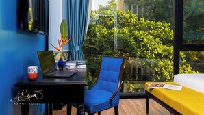 Une chambre d’hôtel équipée d’un bureau, d’un ordinateur portable, d’une chaise et d’un lit recouvert d’une couverture jaune.