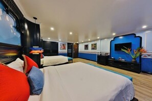 Une chambre d’hôtel avec un grand lit, un bureau, une télévision et un mur orné de tableaux.