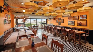 Un restaurant avec de hauts plafonds, de nombreuses tables et des chaises.
