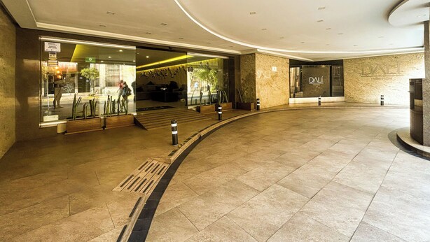 A spacious lobby with a curved ceiling, a reception area, and a DALL Hotel Plaza sign.