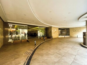 Een ruime lobby met een gebogen plafond, een receptiebalie en een DALL Hotel Plaza bord.
