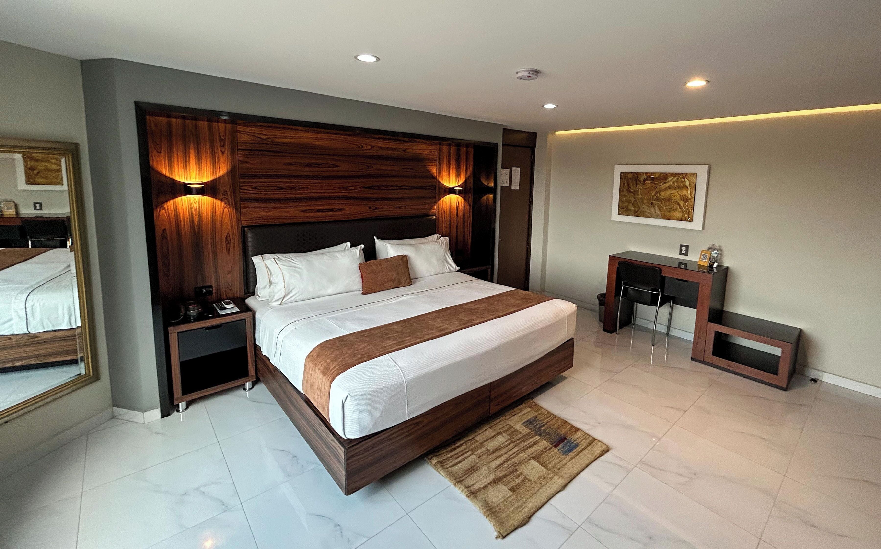 Una habitación de hotel moderna con una cama grande, un escritorio y una pequeña zona de estar.