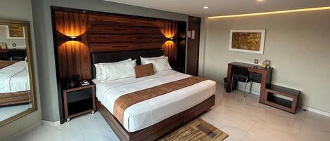 Una habitación de hotel moderna con una cama grande, un escritorio y una pequeña zona de estar.