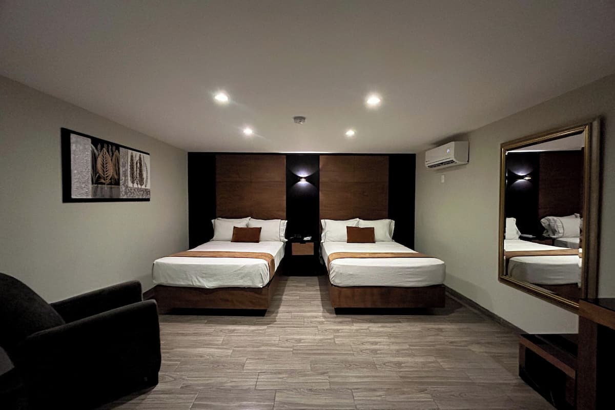 Ein Hotelzimmer mit zwei Betten, einem großen Spiegel, einem gerahmten Bild an der Wand und Holzboden.