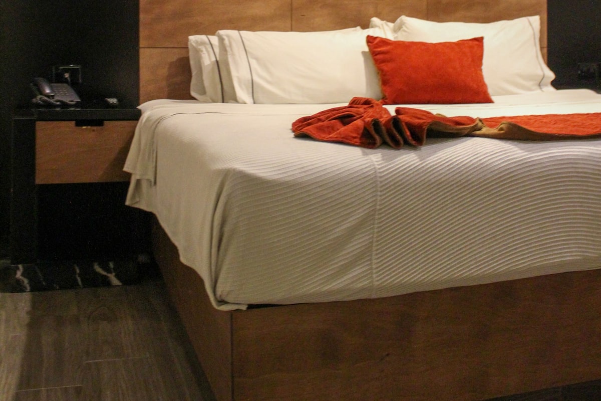 Ein modernes Hotelzimmer mit einem großen Bett, einem Nachttisch und einem an der Wand befestigten Telefon.