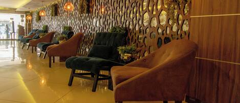 Eine Hotellobby mit einer Reihe von komfortablen Sesseln, einer Wand mit geometrischen Mustern und Pendelleuchten.