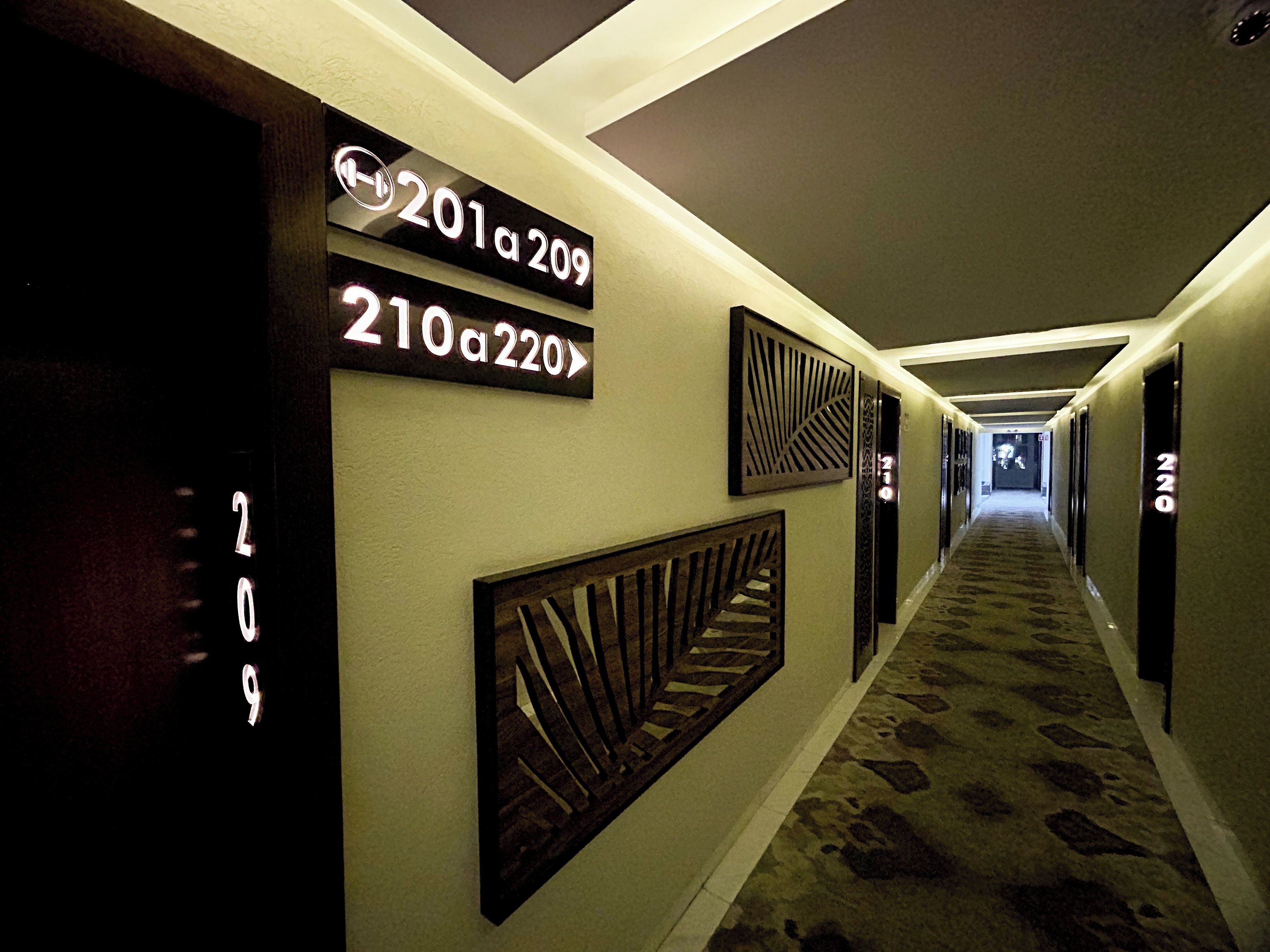 A hotel hallway with directional signs indicating room numbers 201-209 and 210-220.