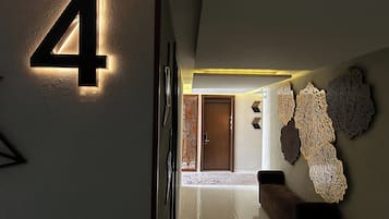 A hallway with a lit number '4' sign, a wooden door, and decorative wall art.