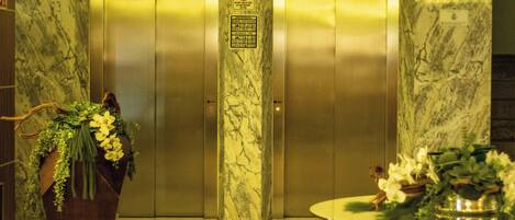 An elevator with marble walls and a sign indicating a maximum capacity of 2 people.