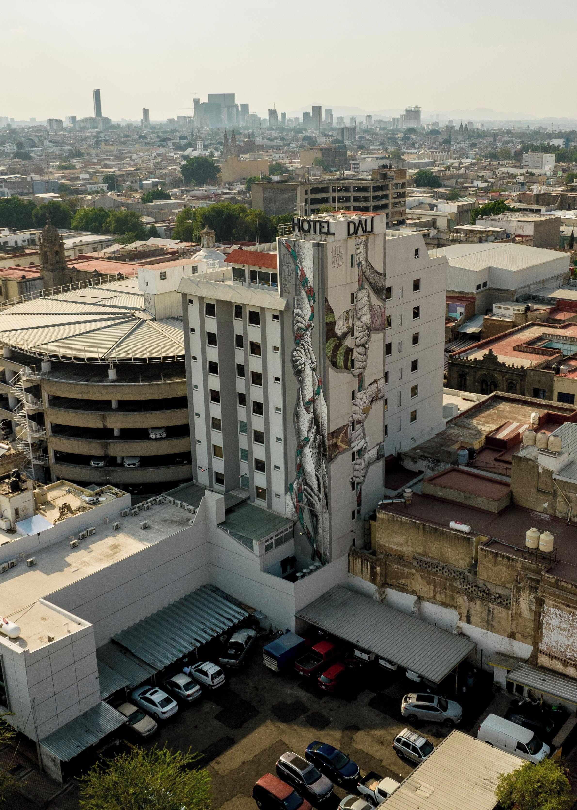 A hotel with a large mural on its facade, multiple parking levels, and a view of the surrounding cityscape.