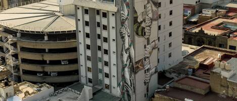 A hotel with a large mural on its facade, multiple parking levels, and a view of the surrounding cityscape.