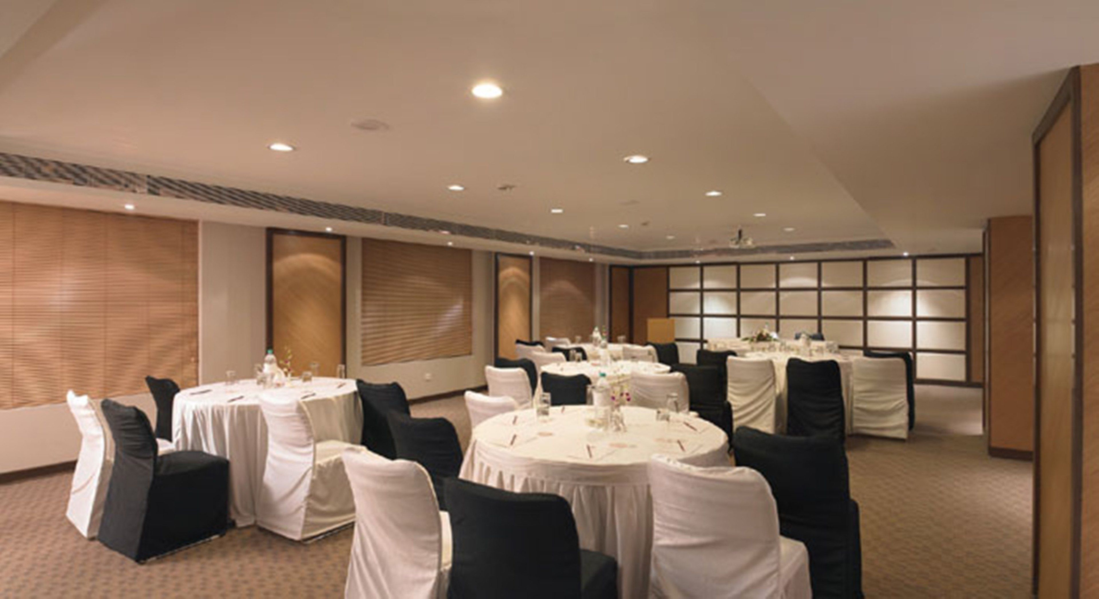 A conference room with multiple round tables, white tablecloths, and black chairs.