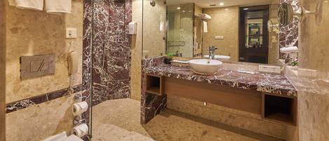 Un baño moderno con tocador de mármol, un espejo grande, una bañera y un inodoro.
