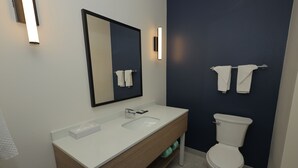 Une salle de bain moderne avec un lavabo blanc, un miroir et des toilettes.