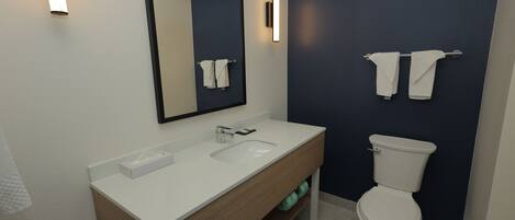 Un baño moderno con un lavamanos, espejo y retrete blancos.