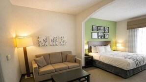 Une chambre d’hôtel avec un lit, un canapé, une table basse et des œuvres d’art murales.
