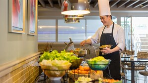 Un buffet proposant une variété de plats, avec un chef de cuisine qui sert les clients.