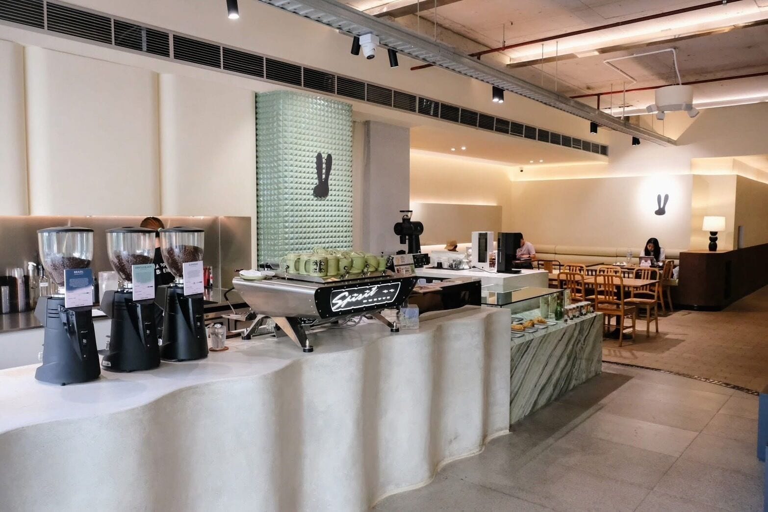 Un café moderne avec un comptoir, des machines à café et un espace salon.