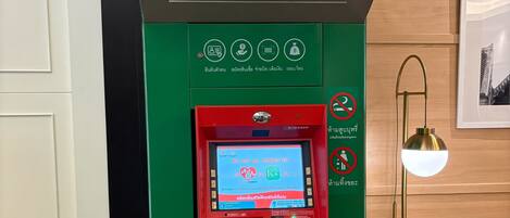An ATM machine with a green and red color scheme, Visa and MasterCard logos, and a sign indicating Thai Baht currency.