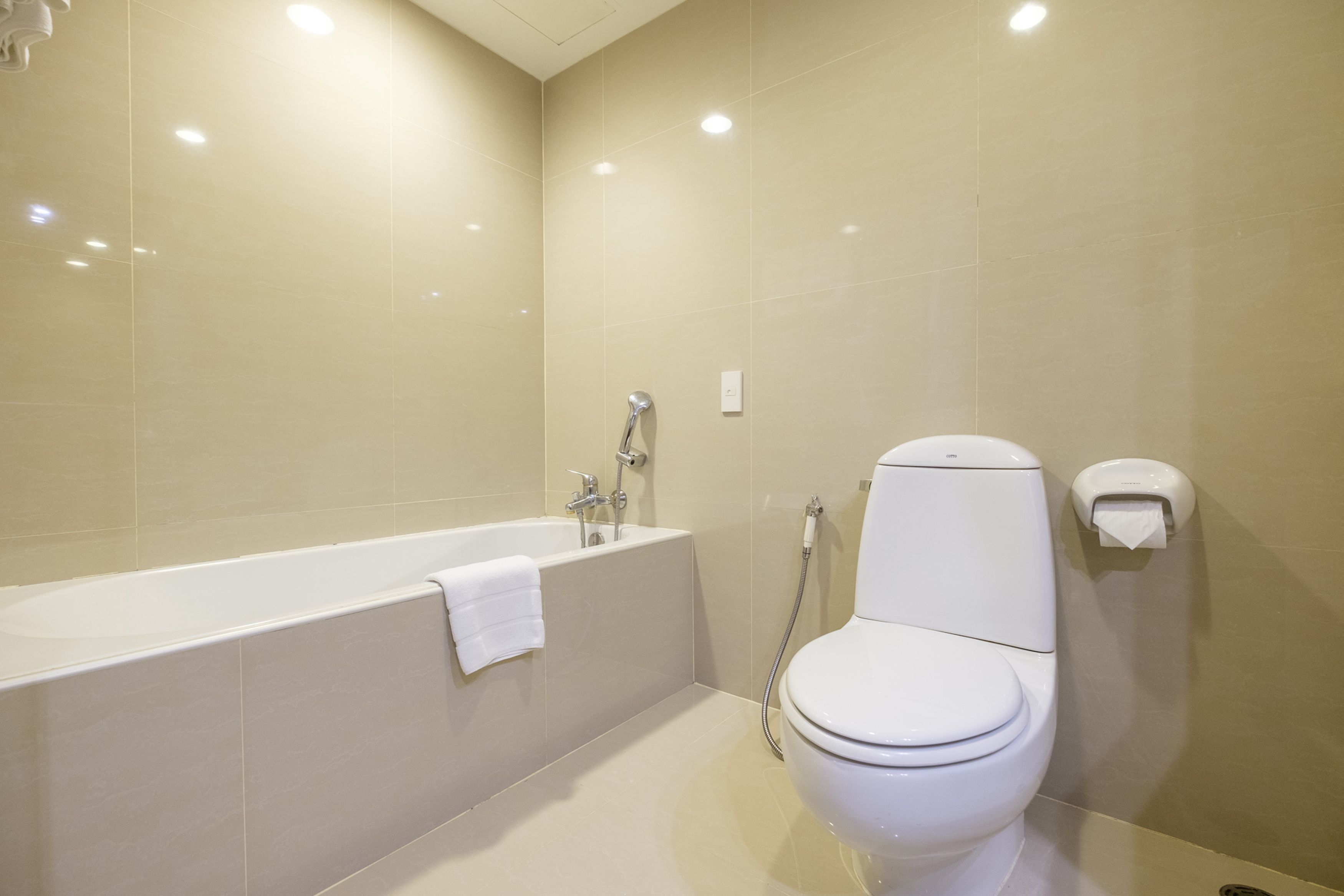 A modern bathroom with a bathtub, toilet, and hand shower.