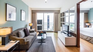 Une chambre d’hôtel avec un canapé, une table basse, une télévision et un lit.