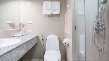 A modern bathroom with a granite countertop, a white toilet, a glass shower enclosure, and a towel rack with two towels.