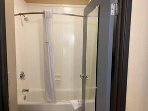 A walk-in shower with a glass door, a shower curtain, and a bathtub. - Baymont Inn And Suites Ft. Leonard/saint Robert (St. Robert)
