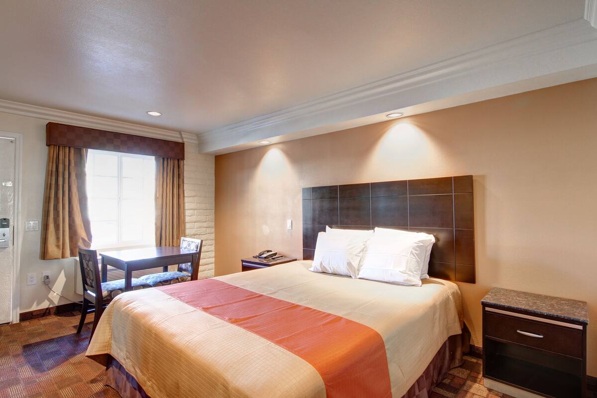A hotel room with a large bed, a desk, and a nightstand.