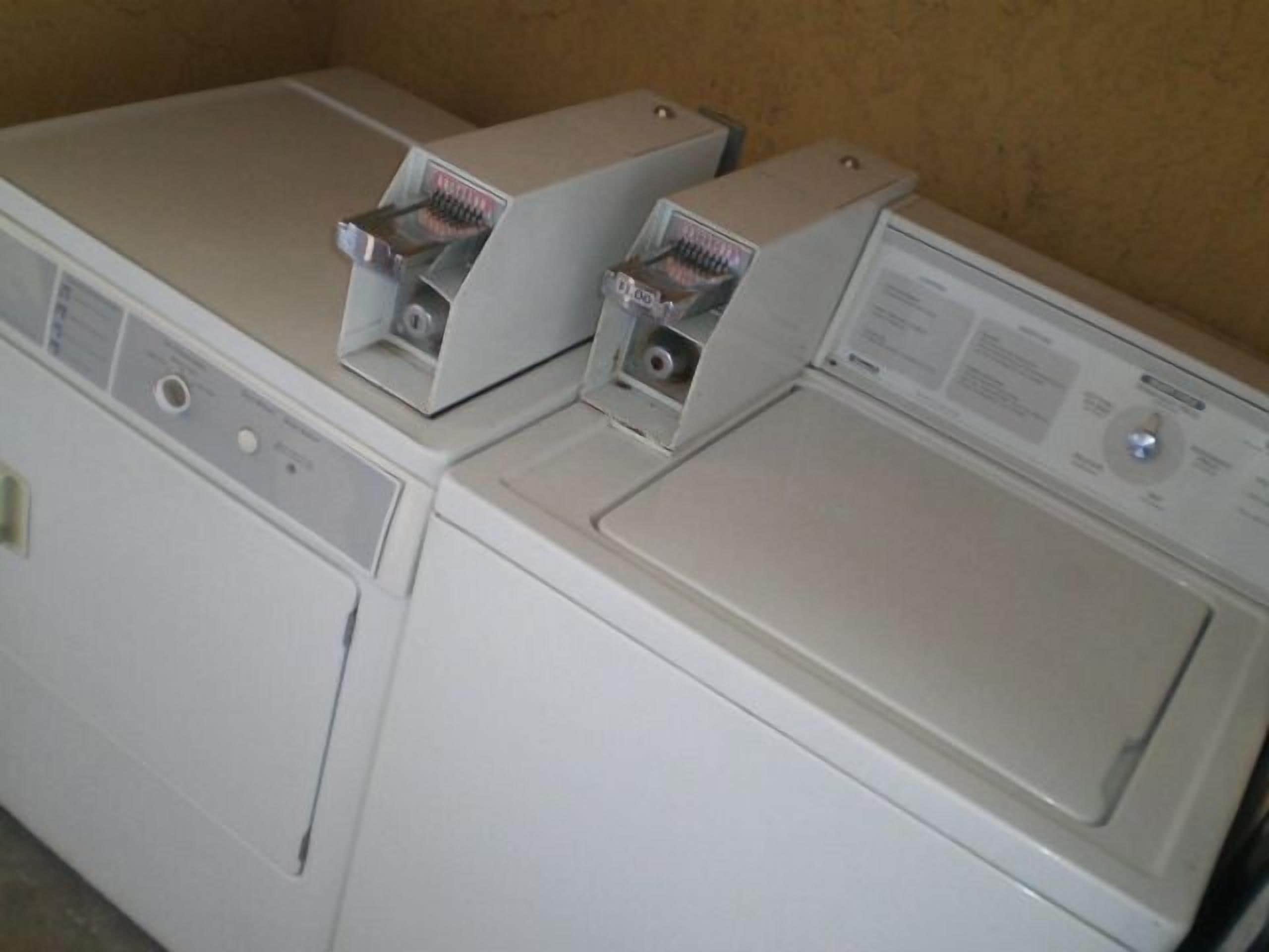 A front view of a laundry room with two stacked washing machines and a dryer.